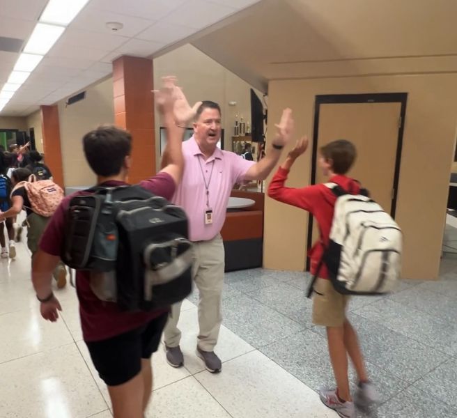  Liberty Middle Principal Shannon Brown high fiving two students walking in their backpacks